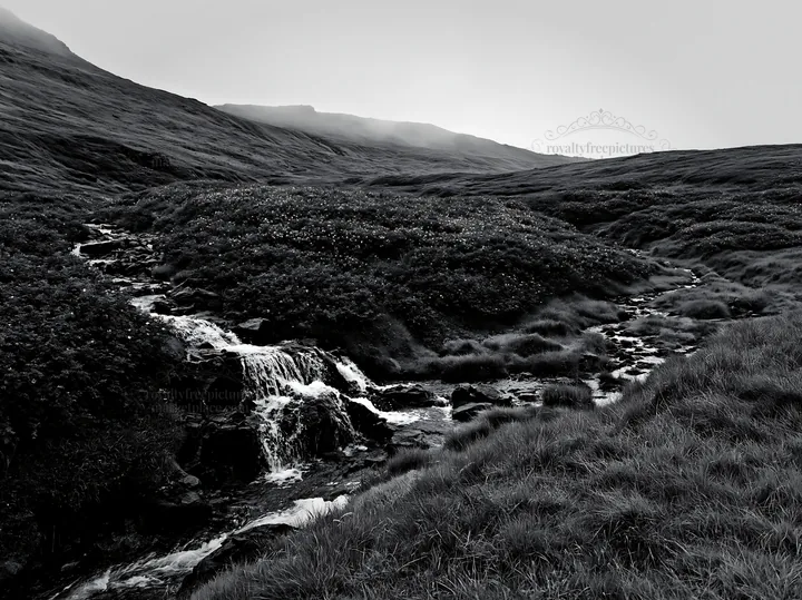 Waterfall flowing through a meadow with hills in the distance - AI-generated stock image